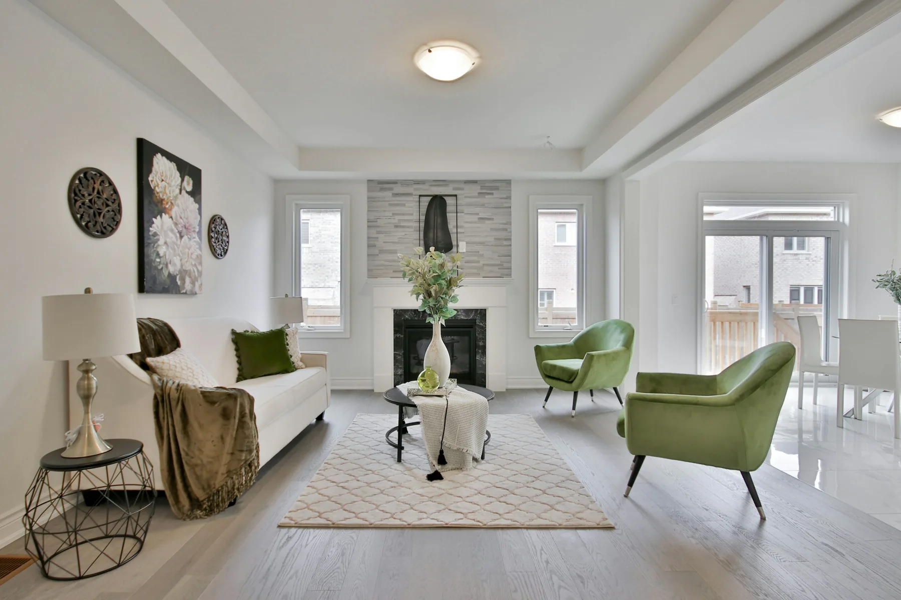 Open living room with white seating, pale floors and green chairs.
